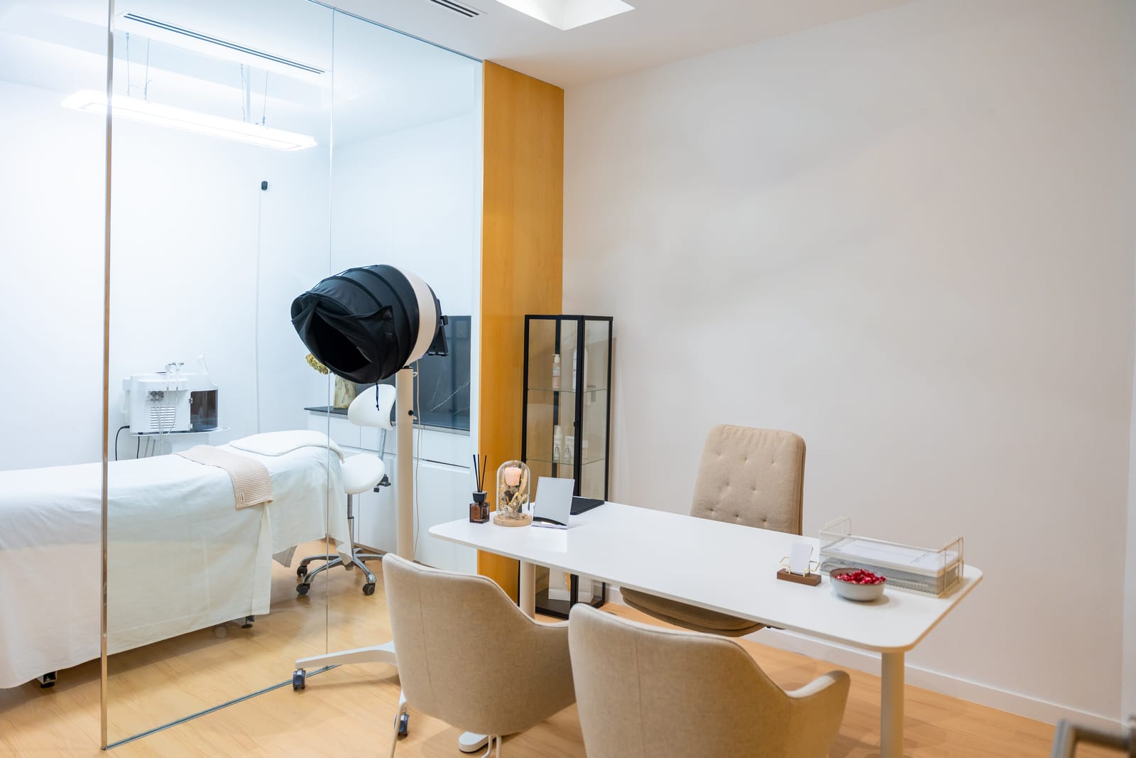 A bright, modern dermatology treatment room with a consultation desk and chairs
