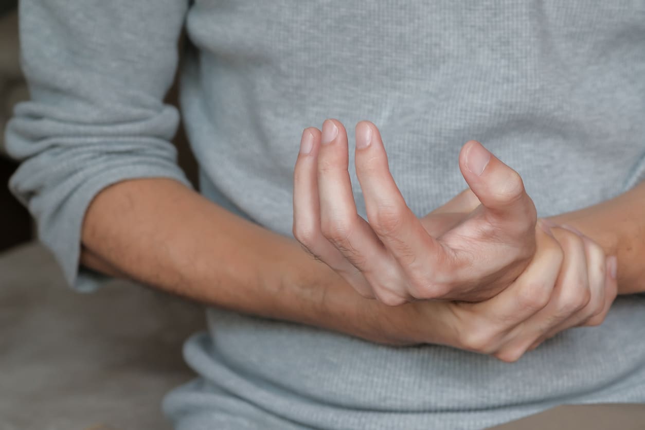 Man experiencing hand weakness related to lupus.